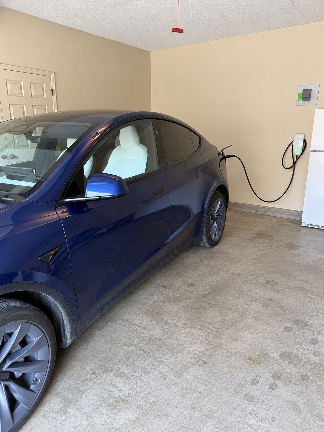 Level 2 charger mounted on a garage wall with the cable connected to a parked EV.